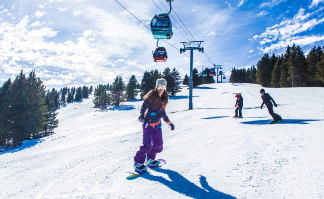 woman snowboarding down slope